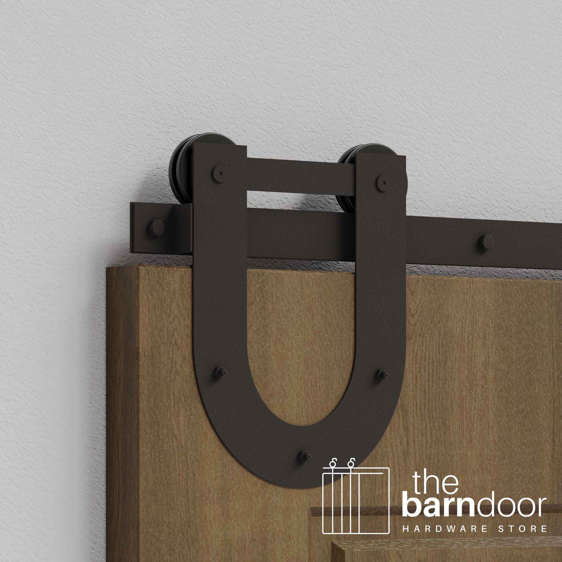 Close-up of Arch Bronze Horseshoe Single Track barn door hardware installed on a wooden door panel.