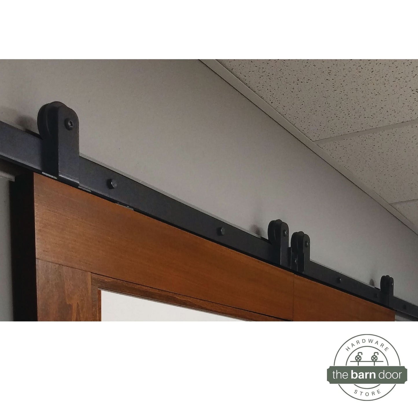 Close-up of Black Straight Top Mount Single Track barn door hardware installed on biparting wooden door panels.