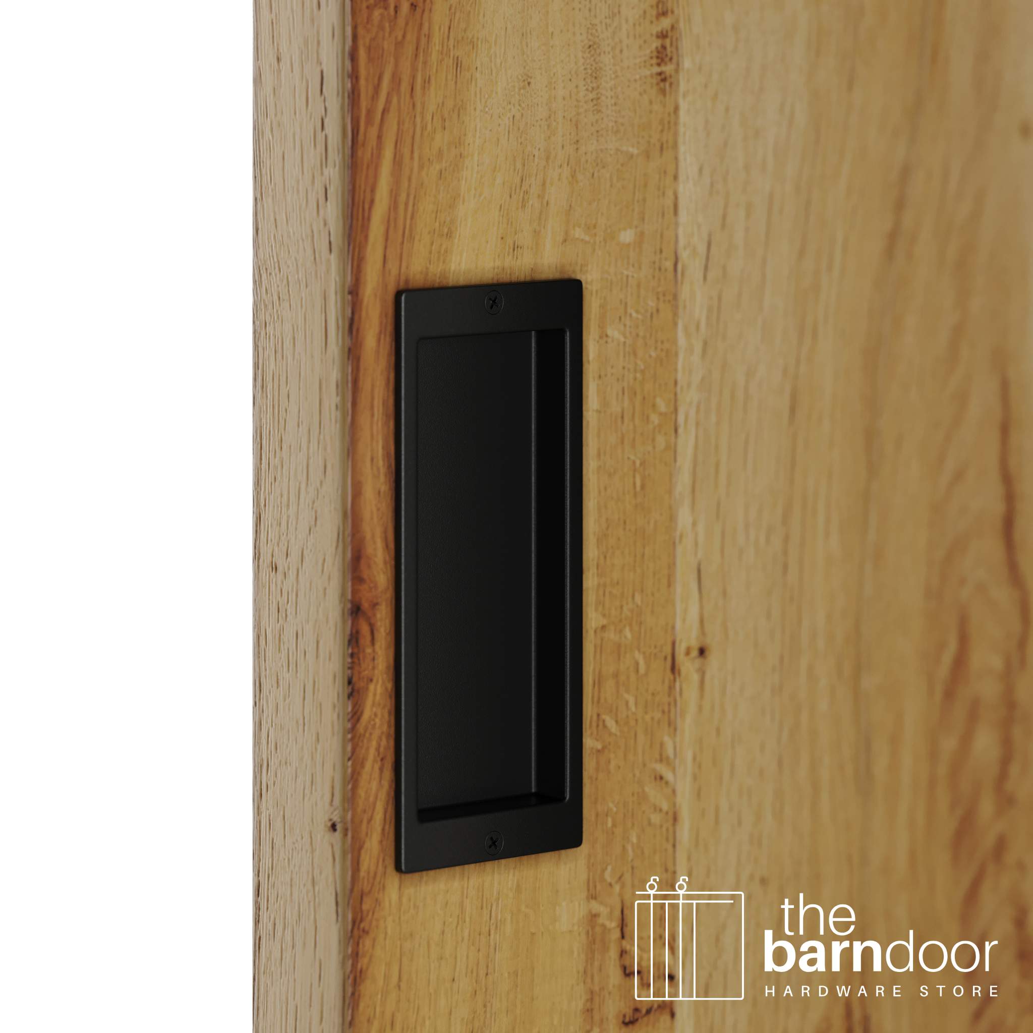 A close-up shot of a recessed rectangular flush pull handle in a black finish, installed on a light brown wooden barn door.