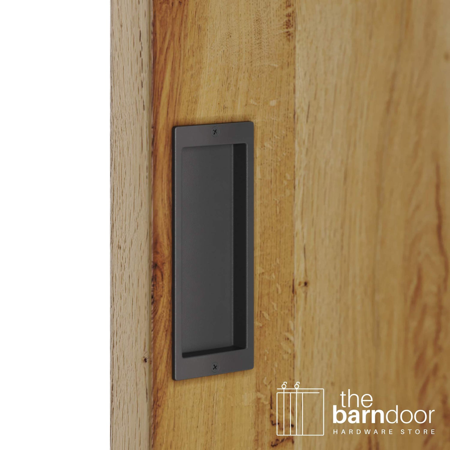 A close-up shot of a recessed rectangular flush pull handle in a dark gray finish, installed on a light brown wooden barn door.