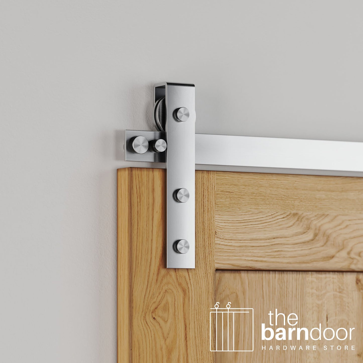 Close-up of Stainless Steel Flat Top Strap barn door hardware installed on a natural wood door, emphasizing the clean, contemporary metal finish.