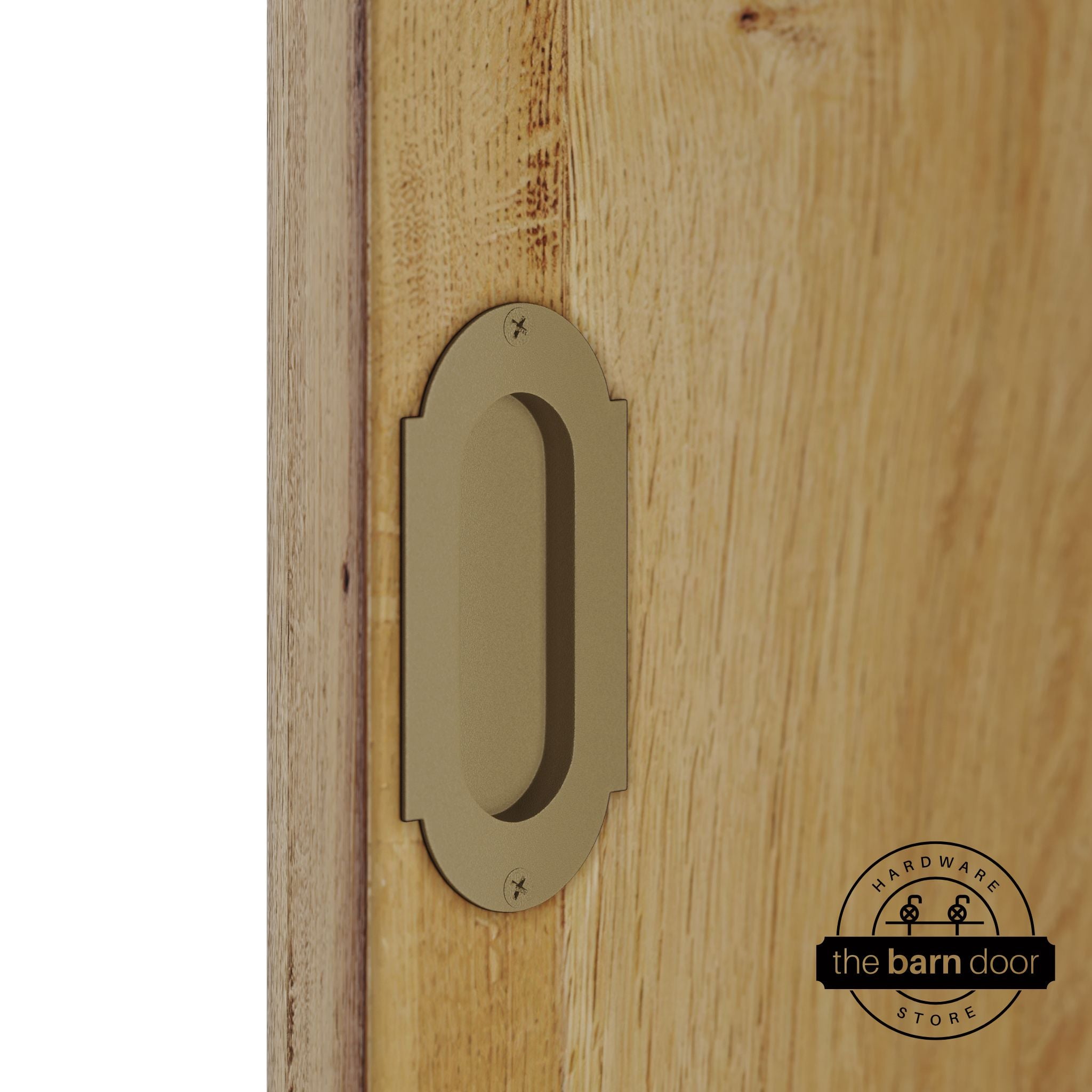 Gold flush pull handle with full radius wings mounted on a light oak barn door, brushed silver finish with oval recessed grip and four mounting screws