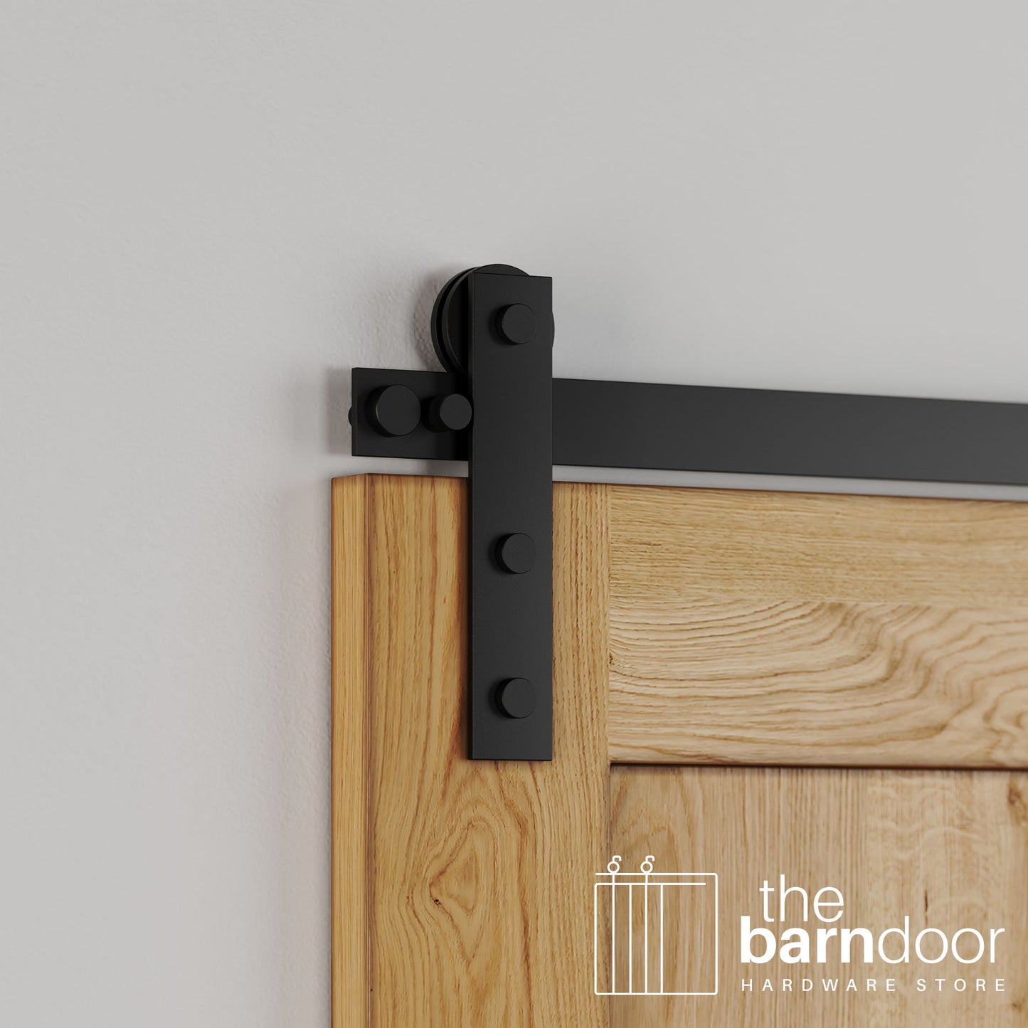 Close-up of Black Stainless Steel Soft-Corner Strap barn door hardware installed on a natural oak wood door, showing the visible strap and smooth roller.