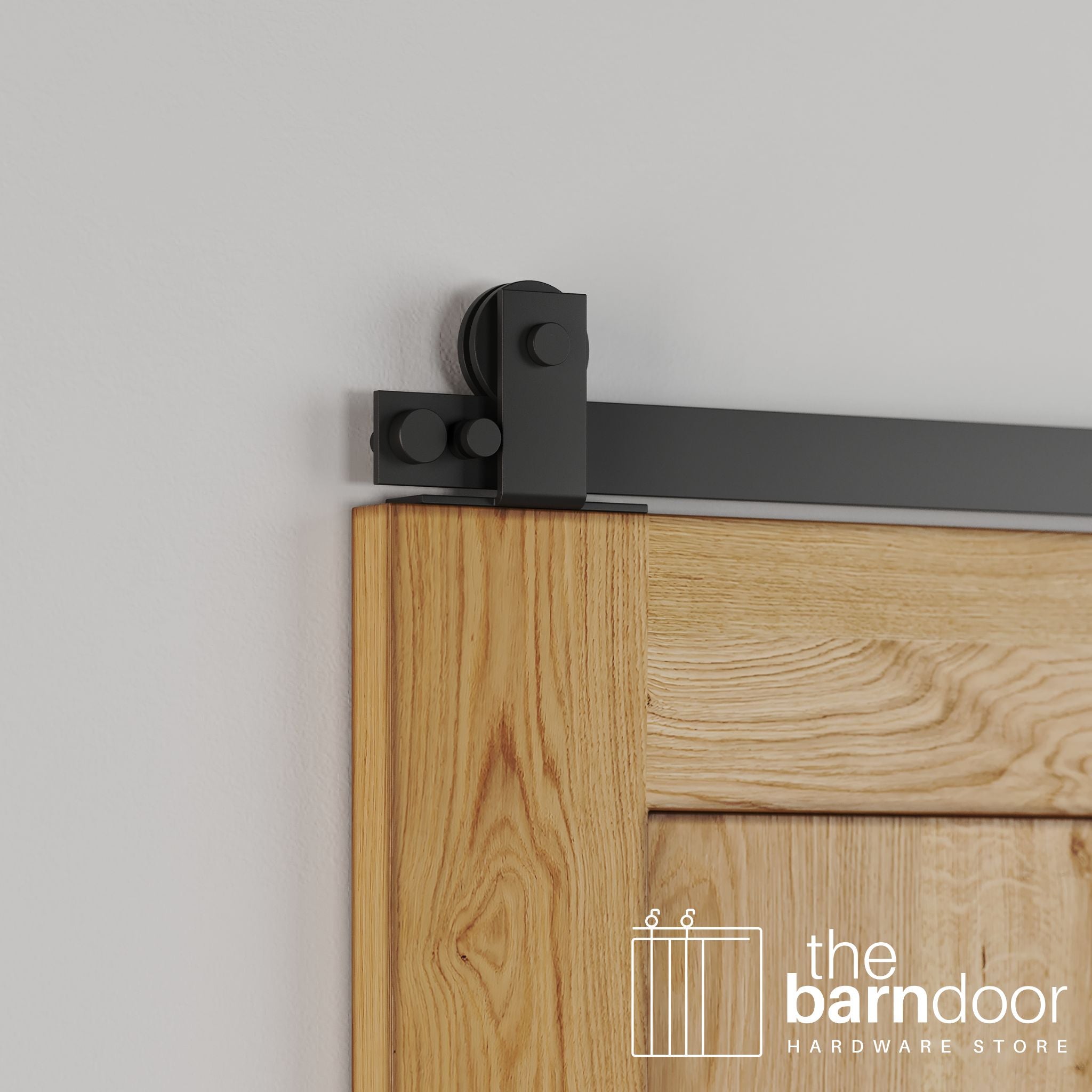 Close-up of Matte Black Stainless Steel Soft-Corner Top Mount barn door hardware installed on the top edge of a natural oak wood door.