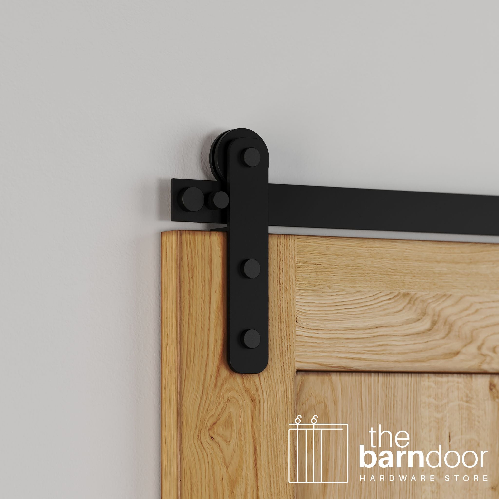 Close-up of Black Stainless Steel Straight Strap barn door hardware installed on a natural oak wood door, showing the vertical strap hanger and visible roller wheel.