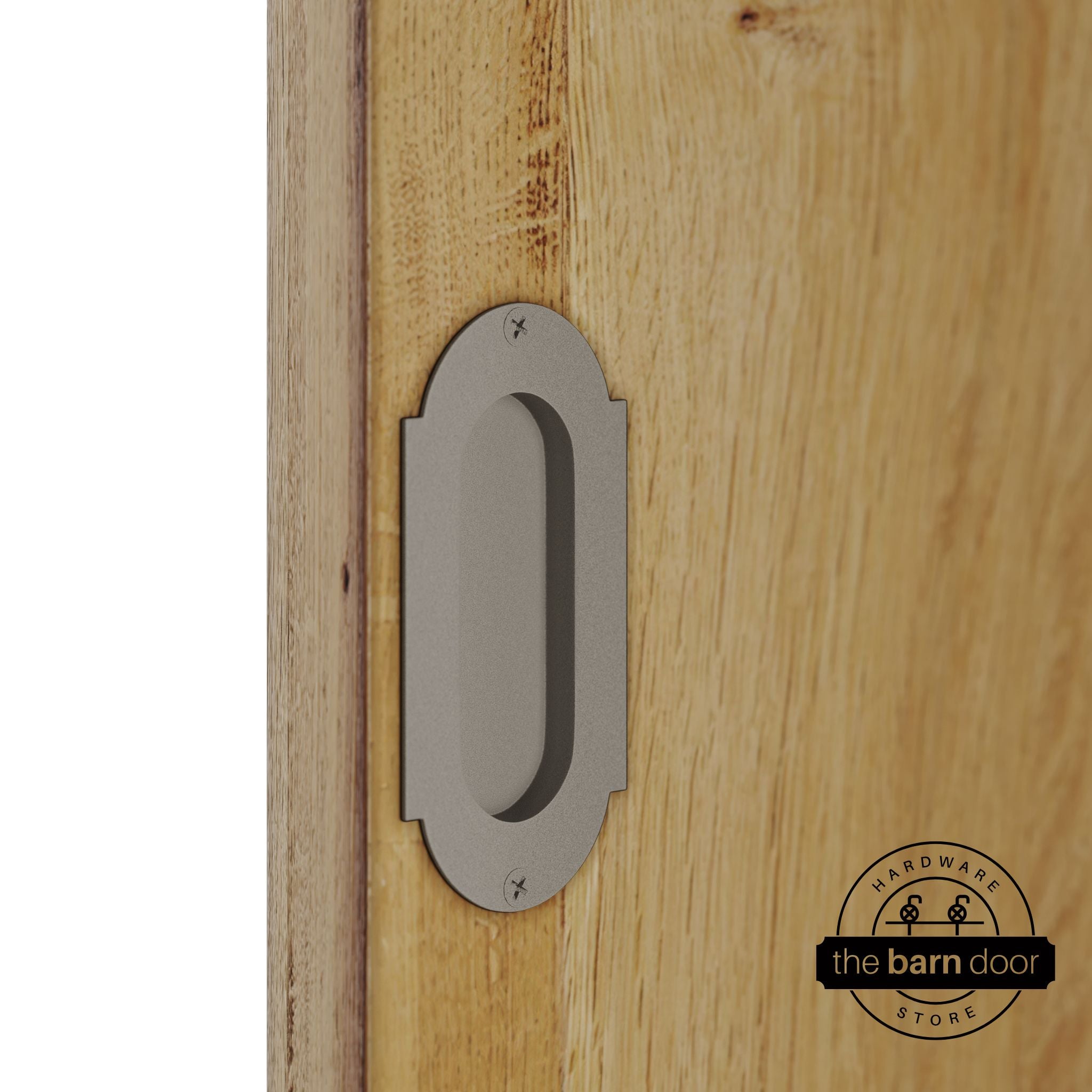 White bronze flush pull handle with full radius wings mounted on a light oak barn door, brushed silver finish with oval recessed grip and four mounting screws