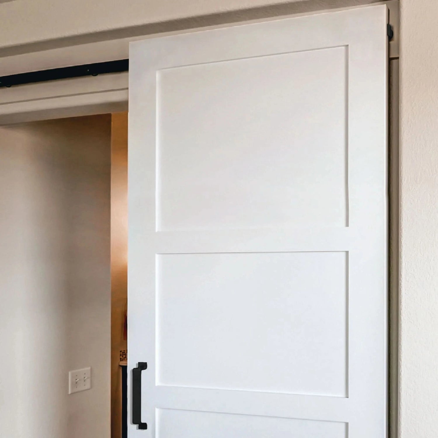 A white three-panel shaker barn door installed with a hidden top-mount track, a clean and modern example of minimalist barn door hardware.
