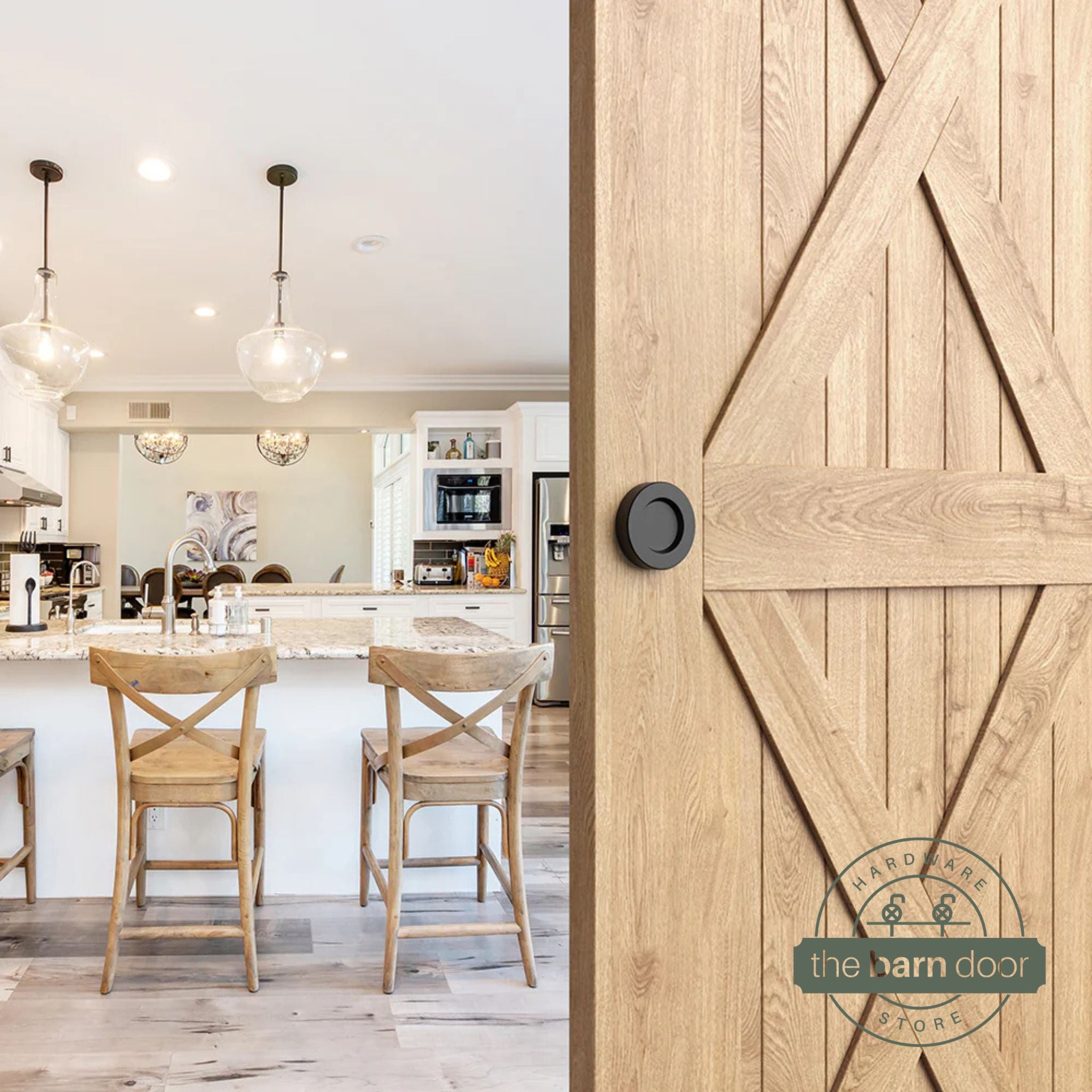 Matte black circular flush pull handle installed on a natural wood barn door in a kitchen setting