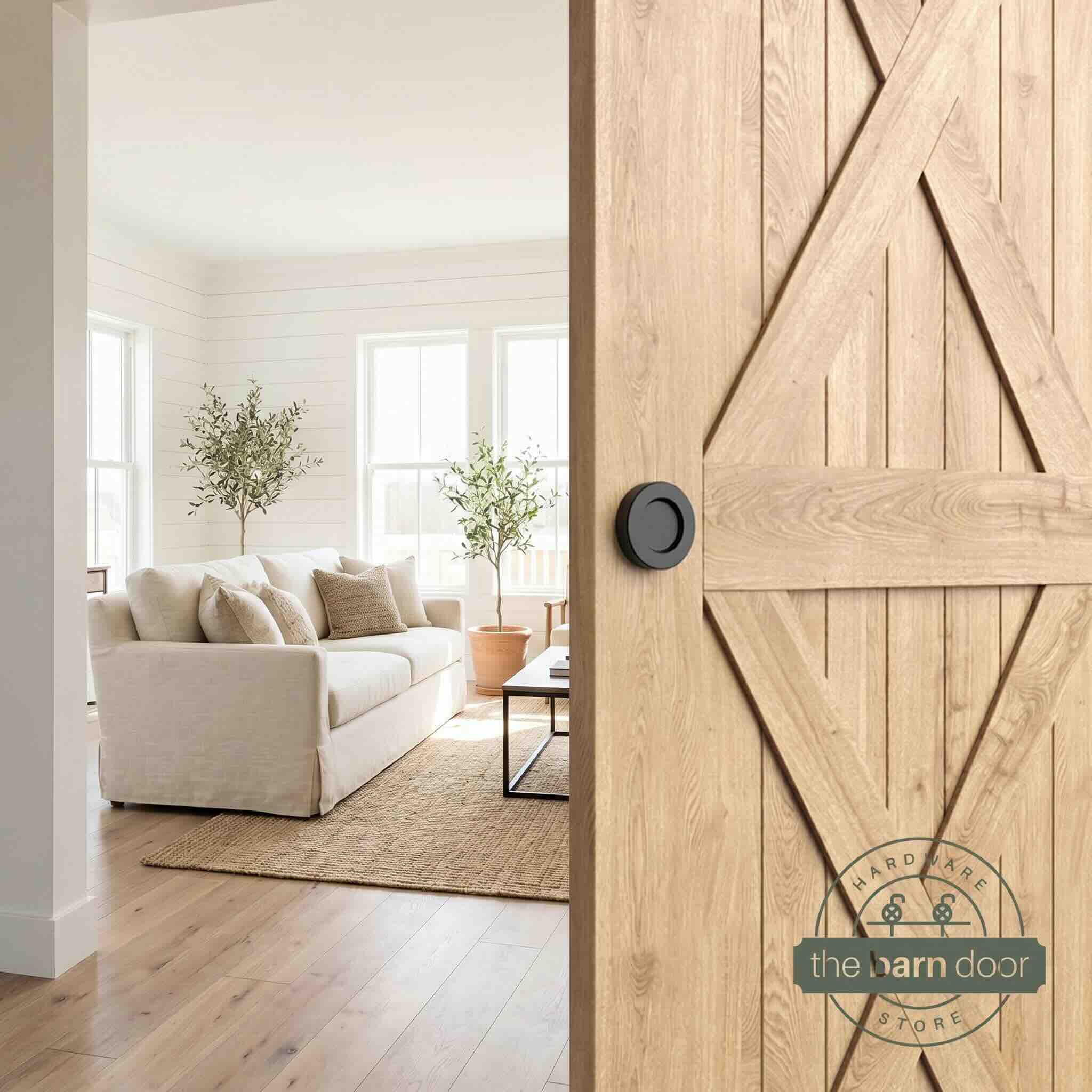 Matte black circular flush pull handle installed on a natural wood barn door in a kitchen setting