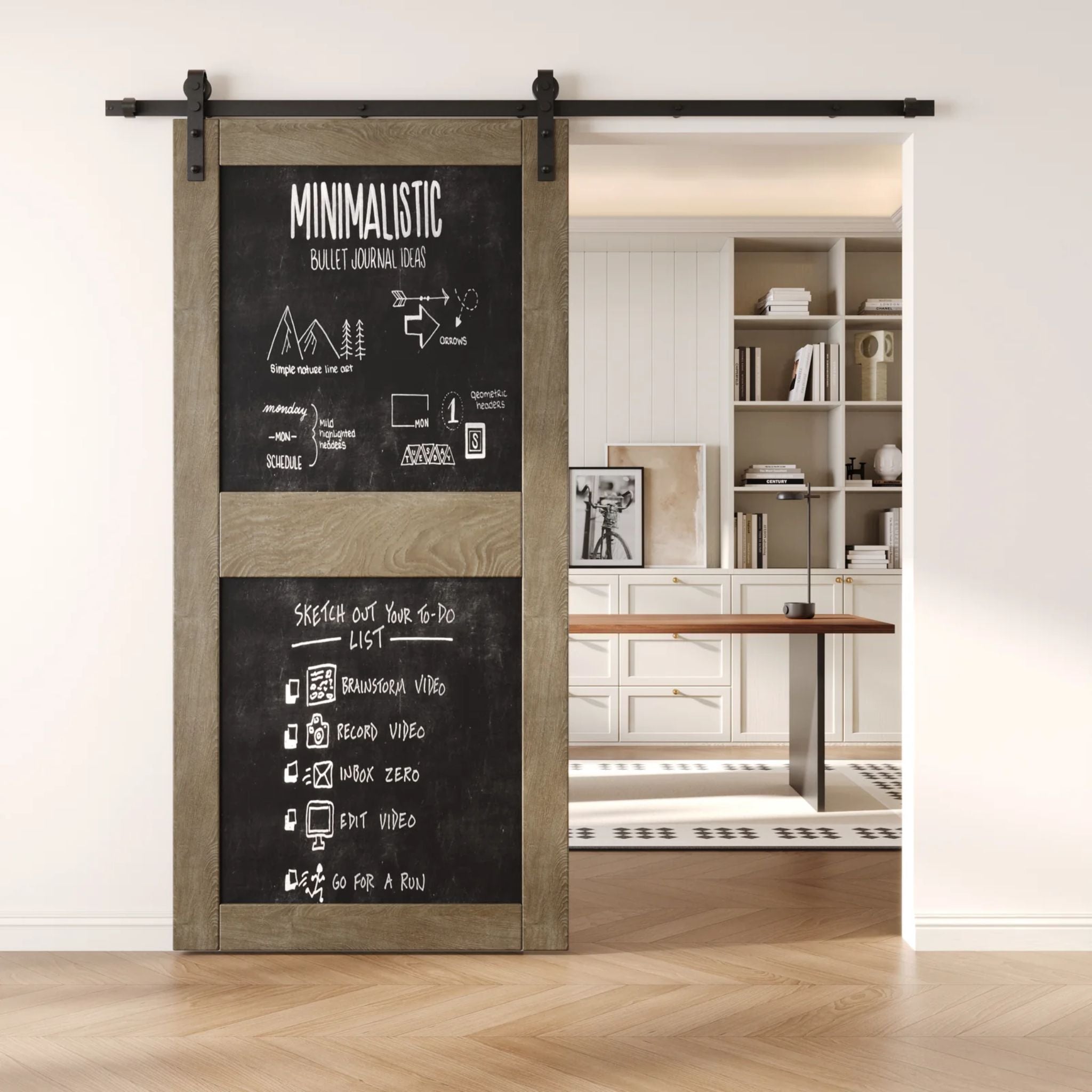 A classic gray two-panel chalkboard barn door mounted on a sleek black sliding track, shown partially open to reveal a modern home office with built-in white shelving.