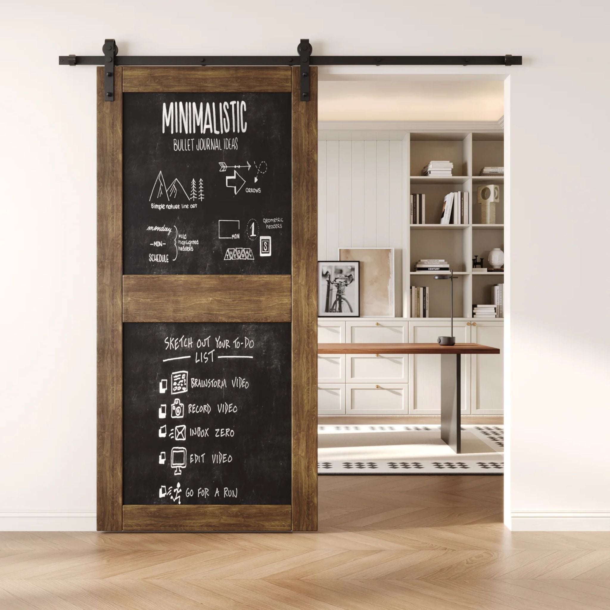 A dark walnut two-panel chalkboard barn door mounted on a sleek black sliding track, shown partially open to reveal a modern home office with built-in white shelving.