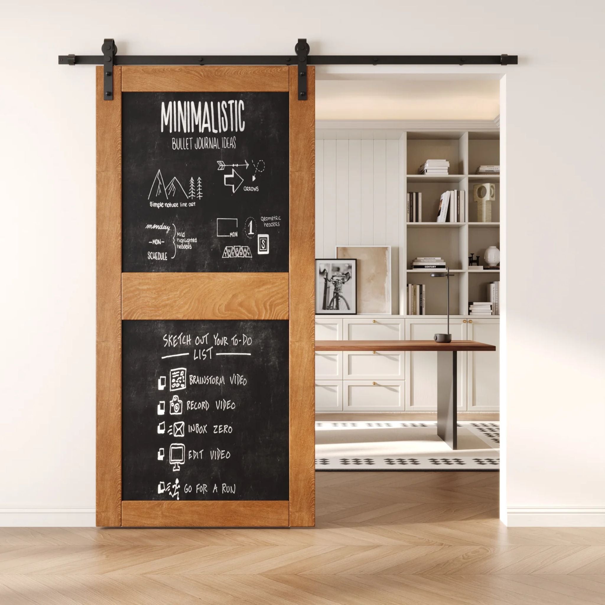 An Early American two-panel chalkboard barn door mounted on a sleek black sliding track, shown partially open to reveal a modern home office with built-in white shelving.