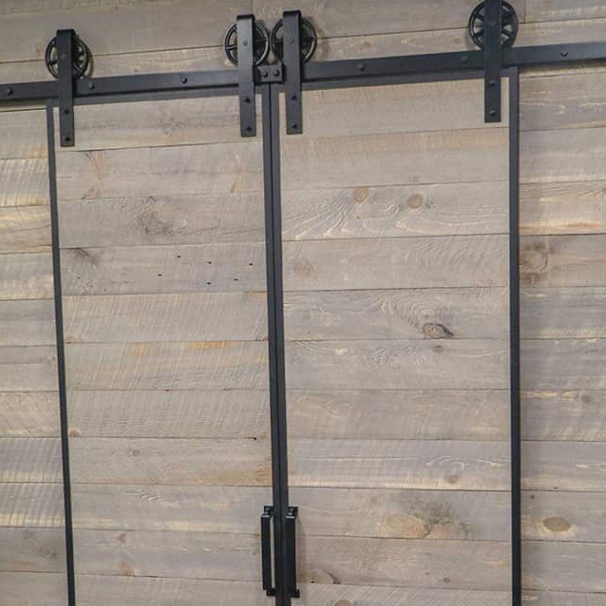 Goldberg Brothers Barn Door Edge Wrap on a double sliding barn door with horizontal reclaimed wood planks and black powder-coated spoke wheel roller hangers