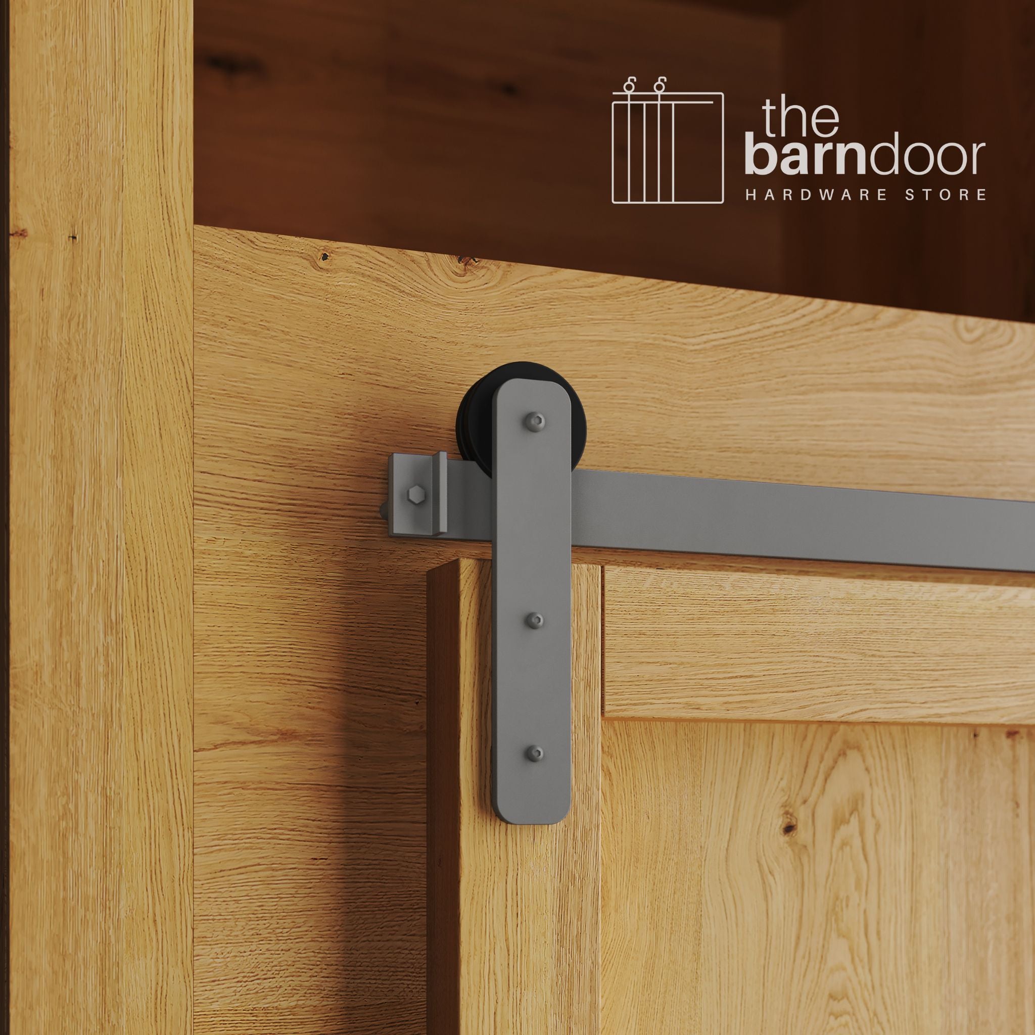 A close-up photograph of a natural oak cabinet with a sliding mini barn door, featuring a flint gray straight-strap hanger and a flint gray track system.