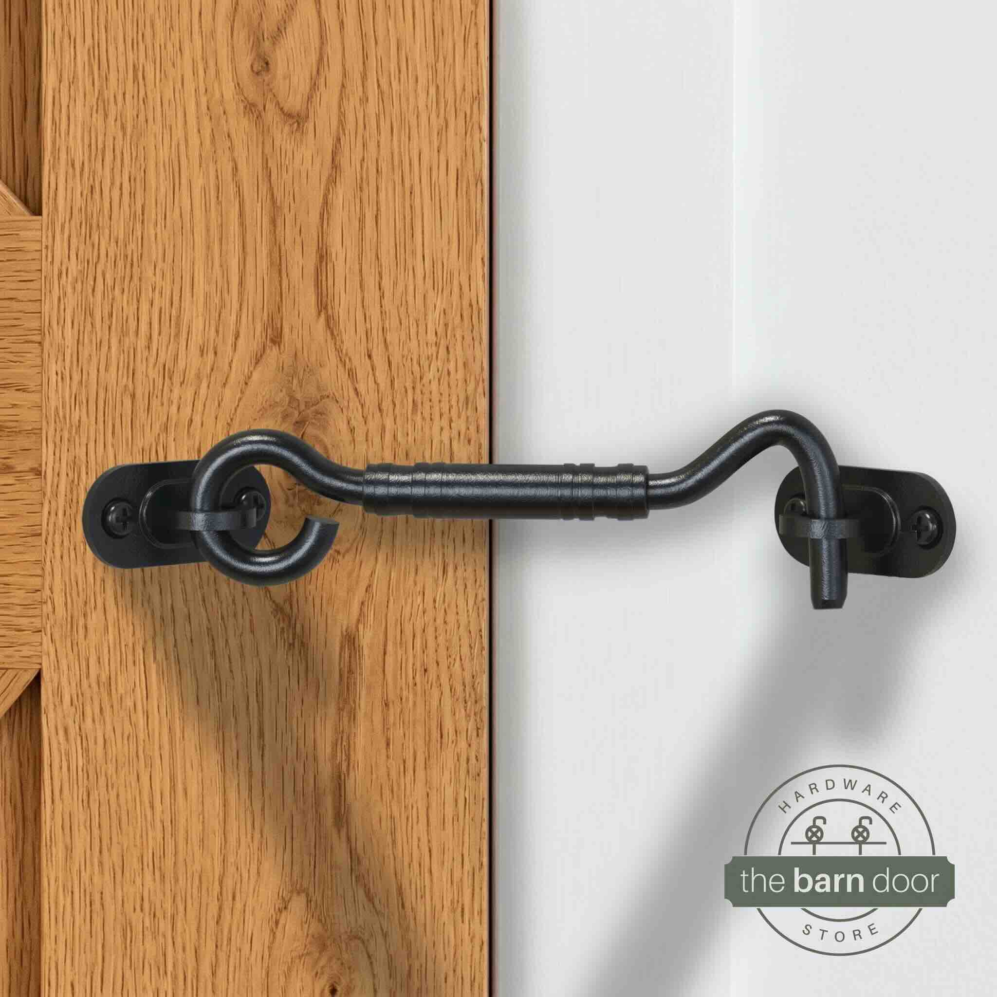 Matte black hook and eye barn door latch securing a light blue door to the adjacent wall