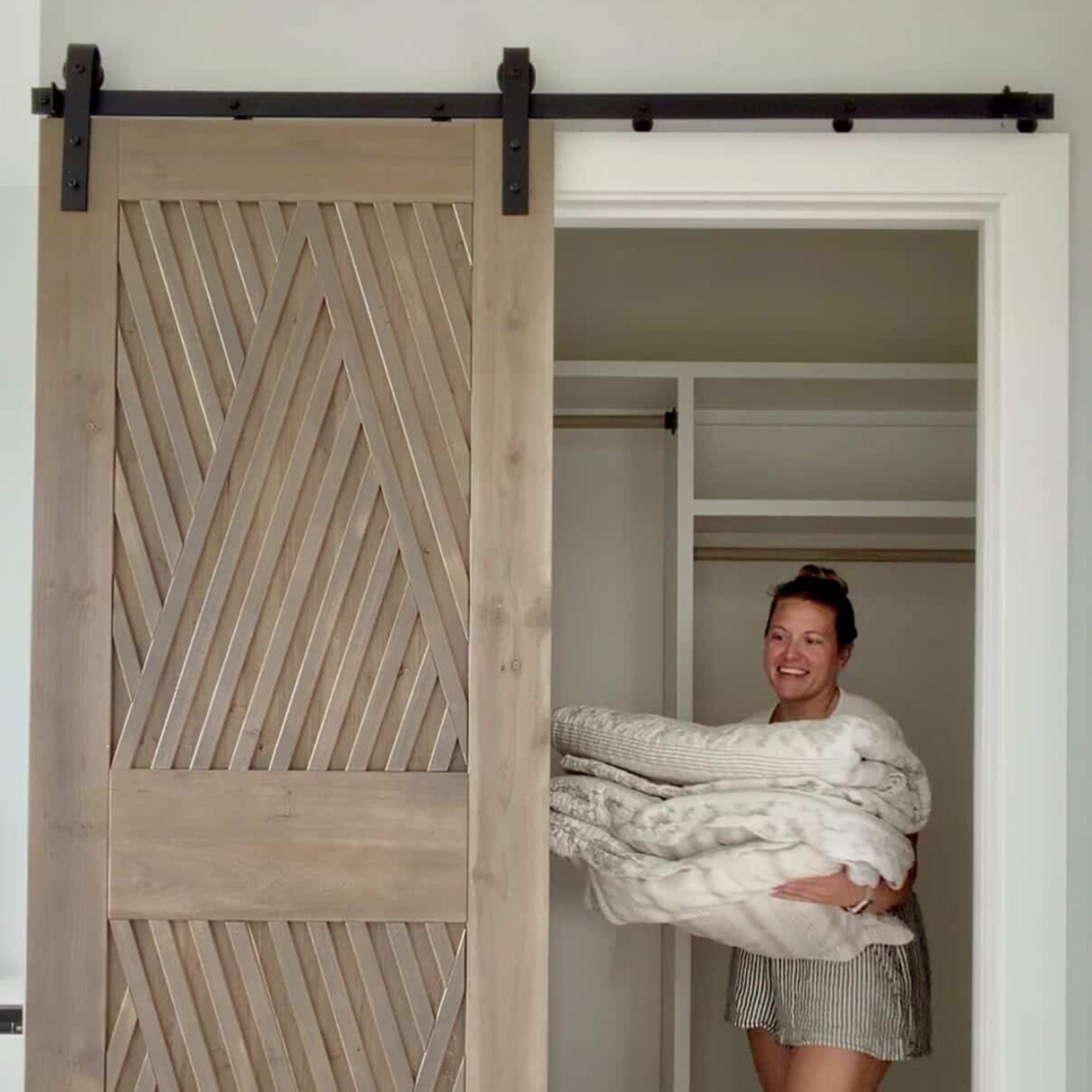 Woman holding blankets in a room with a wooden sliding door