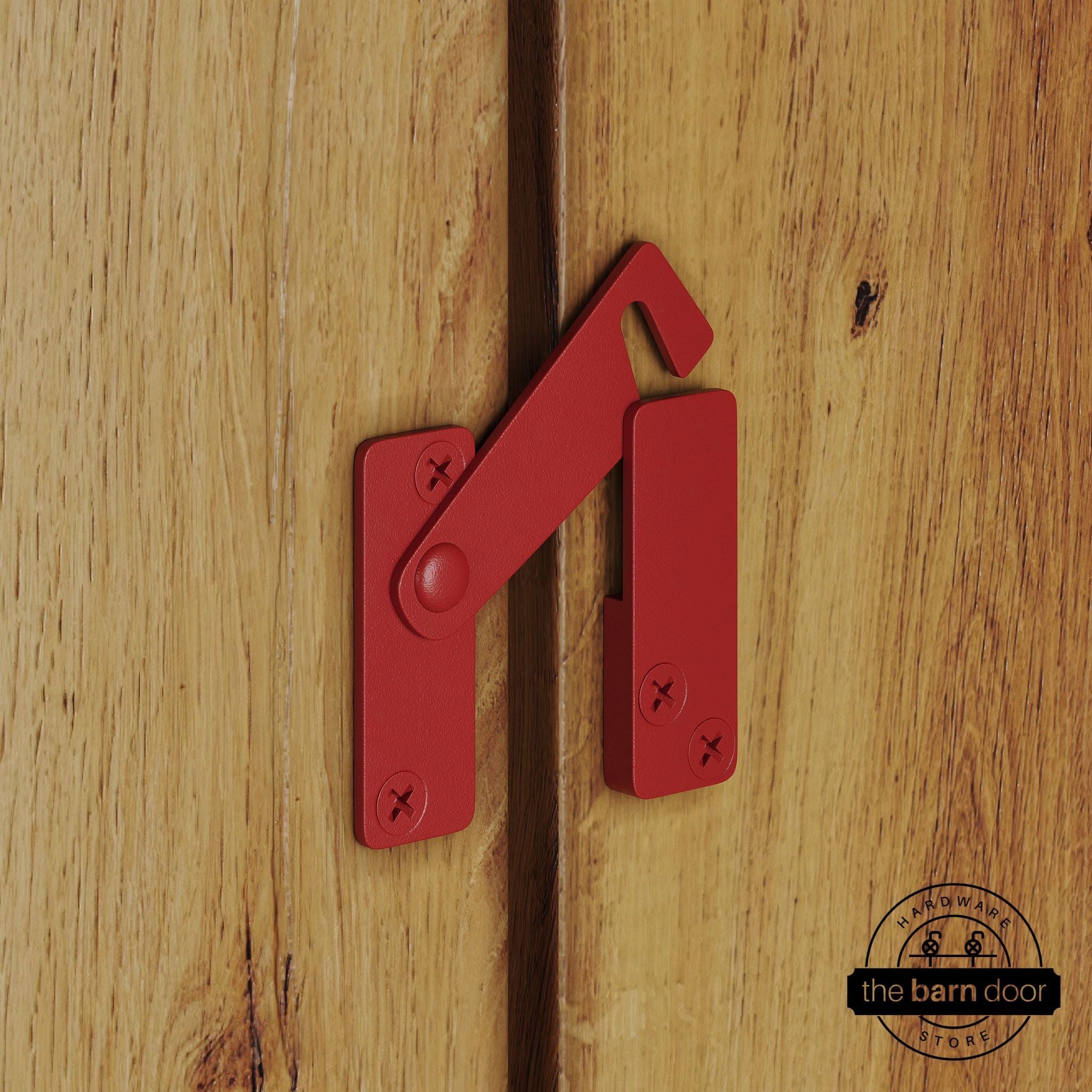 Red privacy latch for biparting barn doors, shown latched across two wood door panels