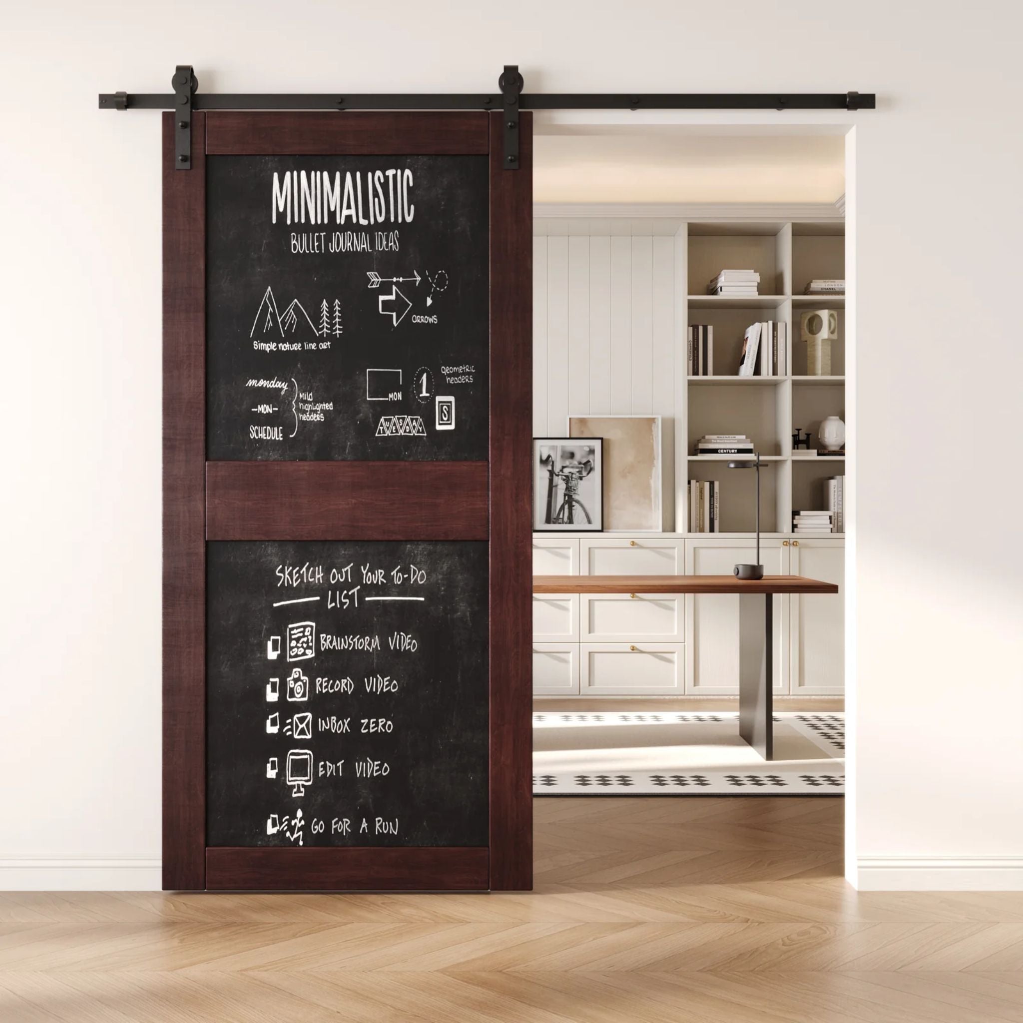A red mahogany two-panel chalkboard barn door mounted on a sleek black sliding track, shown partially open to reveal a modern home office with built-in white shelving.
