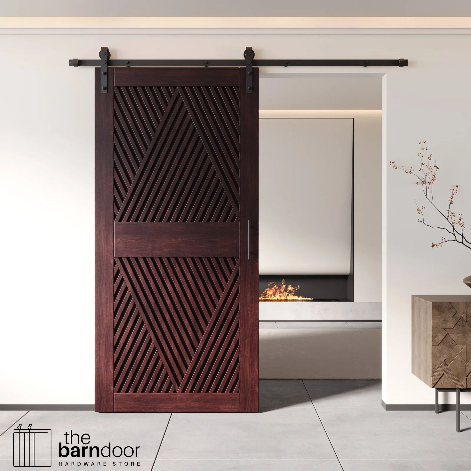 A modern red mahogany barn door with an intricate geometric diamond pattern installed on a black track in a contemporary living space with a fireplace.