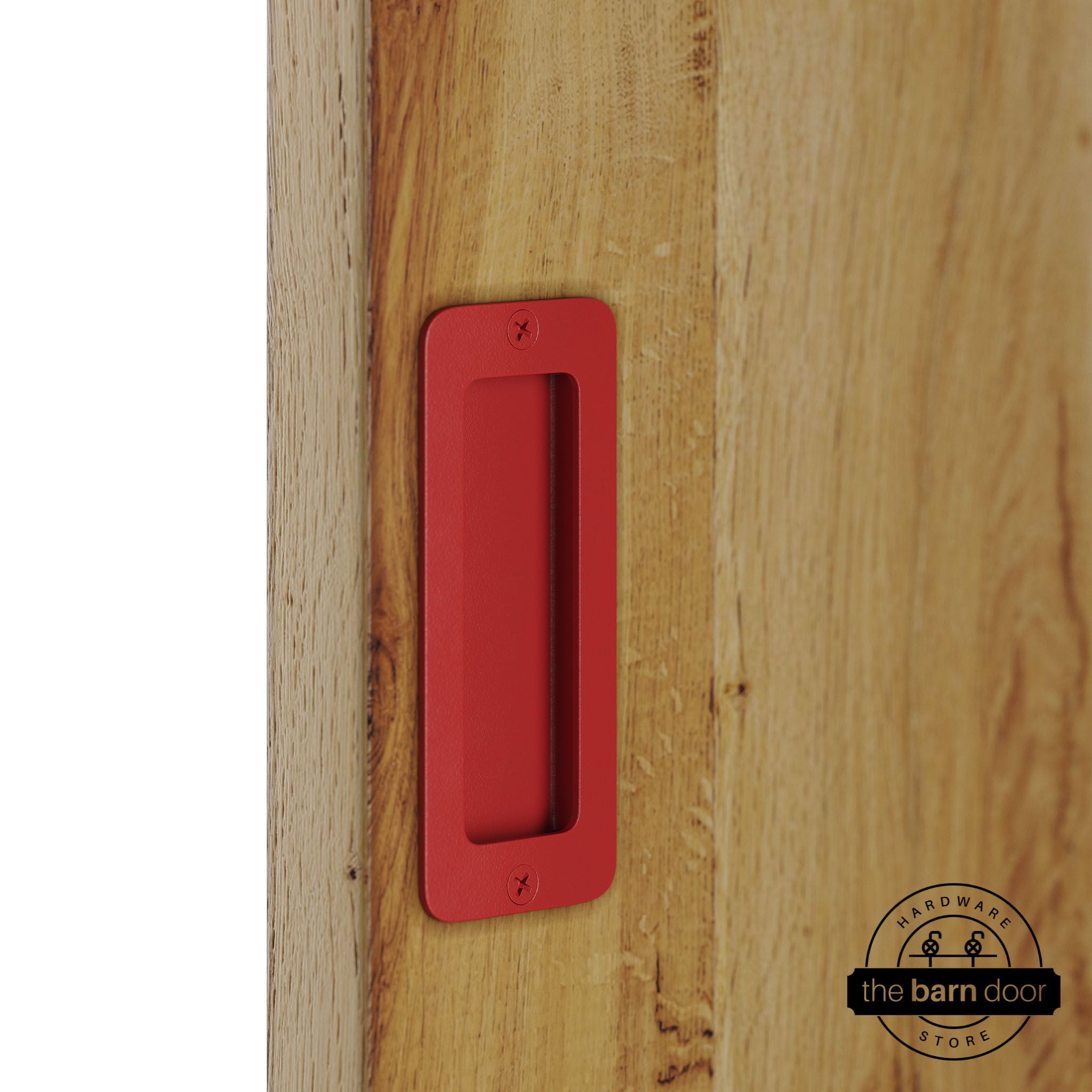 Red partial radius flush pull handle for sliding barn doors, installed on natural wood door panel