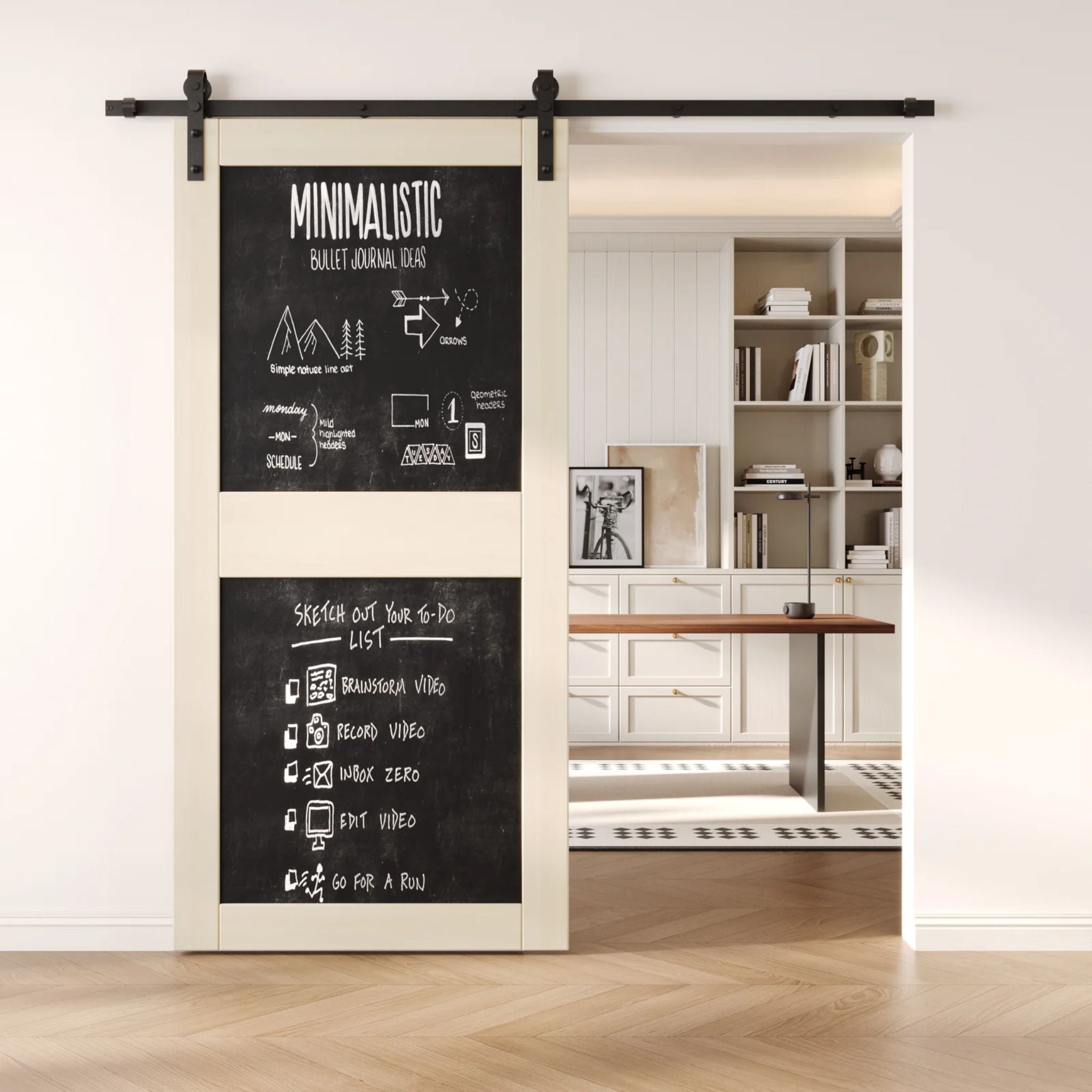 A tinsmith gray two-panel chalkboard barn door mounted on a sleek black sliding track, shown partially open to reveal a modern home office with built-in white shelving.