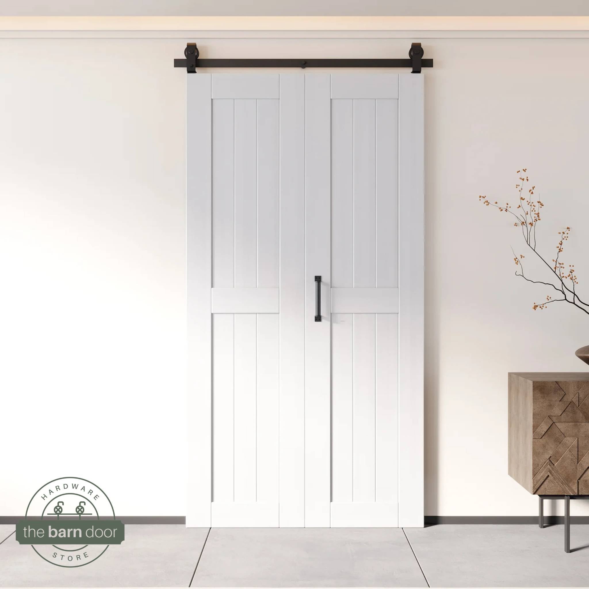 Two-panel bifold barn door in a white finish, installed and fully closed in a modern interior, showing the top-mount Matte Black track.