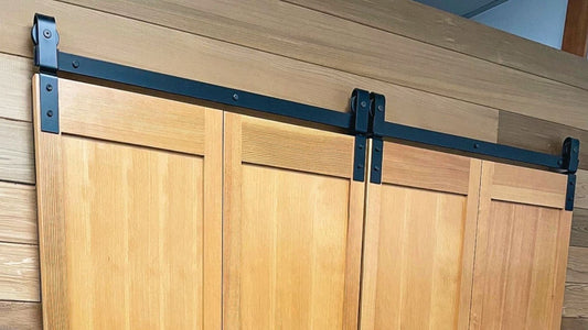 Black bifold barn door hardware on stained wood doors.