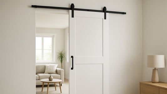 A modern white sliding barn door with black track hardware and a vertical black handle.