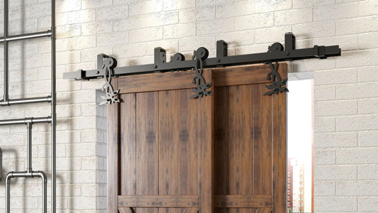 Close-up of two dark wood bypass barn doors hung on black sliding hardware with decorative flower-shaped roller hangers. The doors are set against a white brick wall, with industrial-style piping visible on the left.