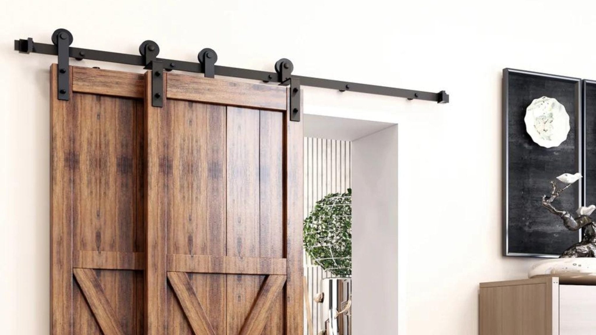 Double bypass sliding barn door hardware kit in matte black, featuring dual rustic wood doors on a white wall in a modern farmhouse interior.