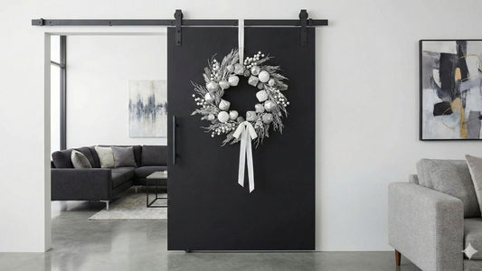 A sleek, matte black barn door with a minimalist flat panel design serves as a room divider in a modern home.