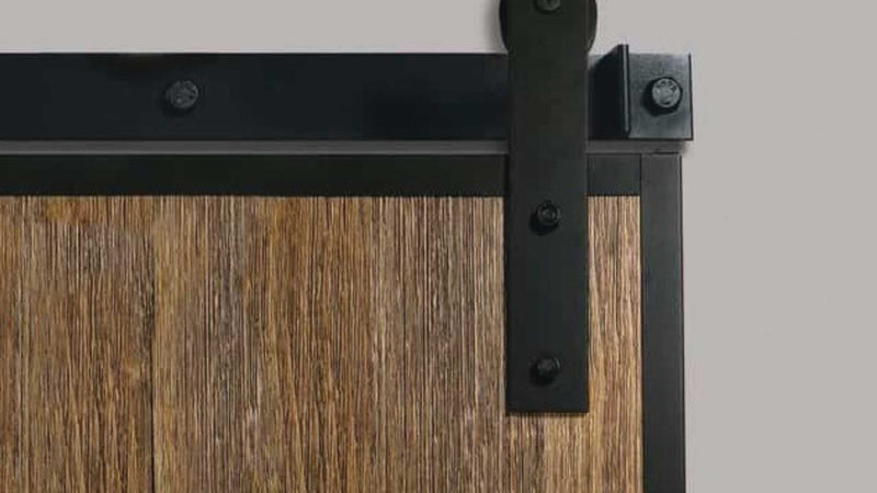 A close-up view of a black edge-wrap barn door hanger bracket and sliding track mounted on a dark stained wood plank door.