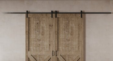 Our heavy-duty barn door hardware installed on two rustic barn doors on a beige plastered wall.