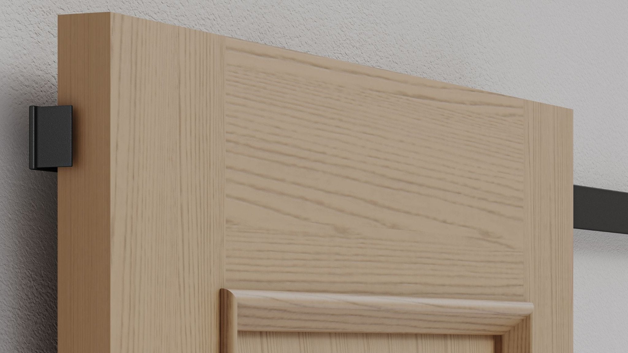 Close-up detail of a light natural wood panel barn door installed with hidden roller hardware, showing only the small, black bracket on the side edge and the concealed track.
