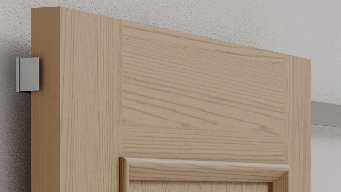 This image shows a close-up of a light-colored wooden sliding door, featuring a minimalist "hidden track" hardware system.