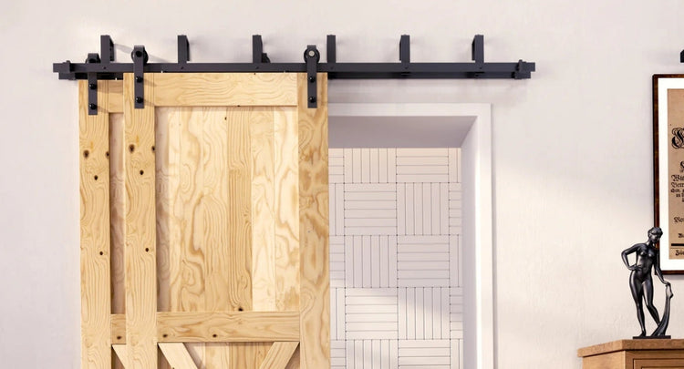 A close-up of a rustic wood barn door with a classic X-brace design, installed with a double bypass barn door hardware kit in a matte black finish.