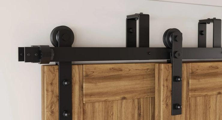 A close-up showcasing the solid steel construction and rollers of our double bypass barn door hardware kit in a matte black finish.