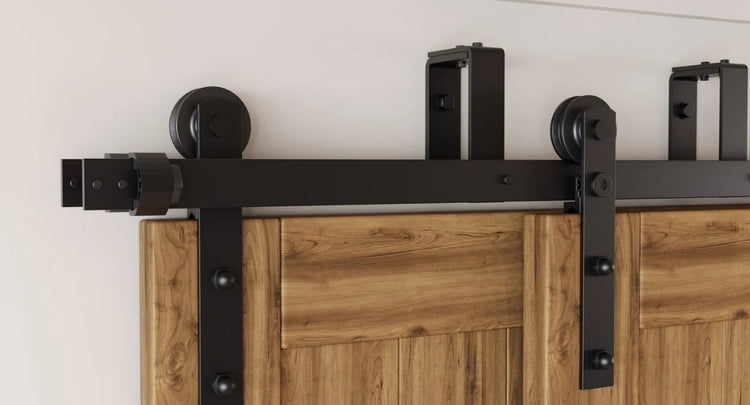 A close-up showcasing the solid steel construction and rollers of our double bypass barn door hardware kit in a matte black finish.
