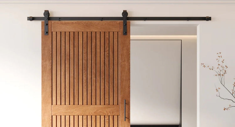  A close-up showcasing a custom-made wood barn door with vertical slat panels and classic J-strap hardware in a matte black finish.