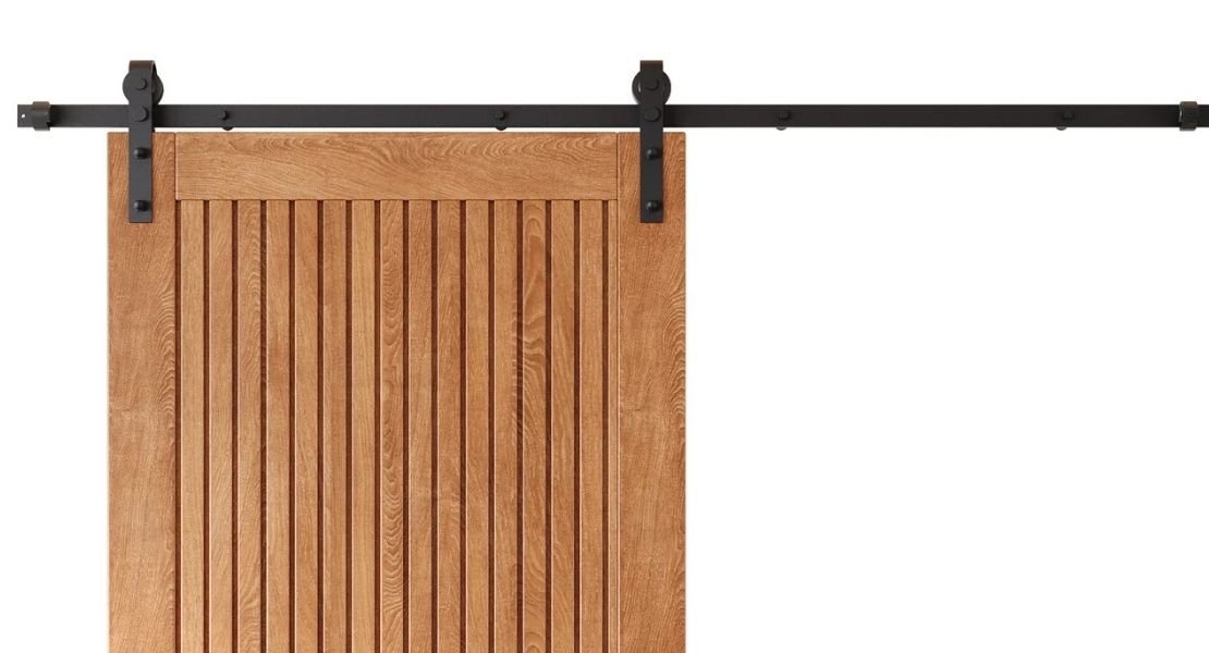 A close-up of the top of a modern farmhouse wood barn door featuring vertical grooved paneling and black bent-strap rolling hardware.