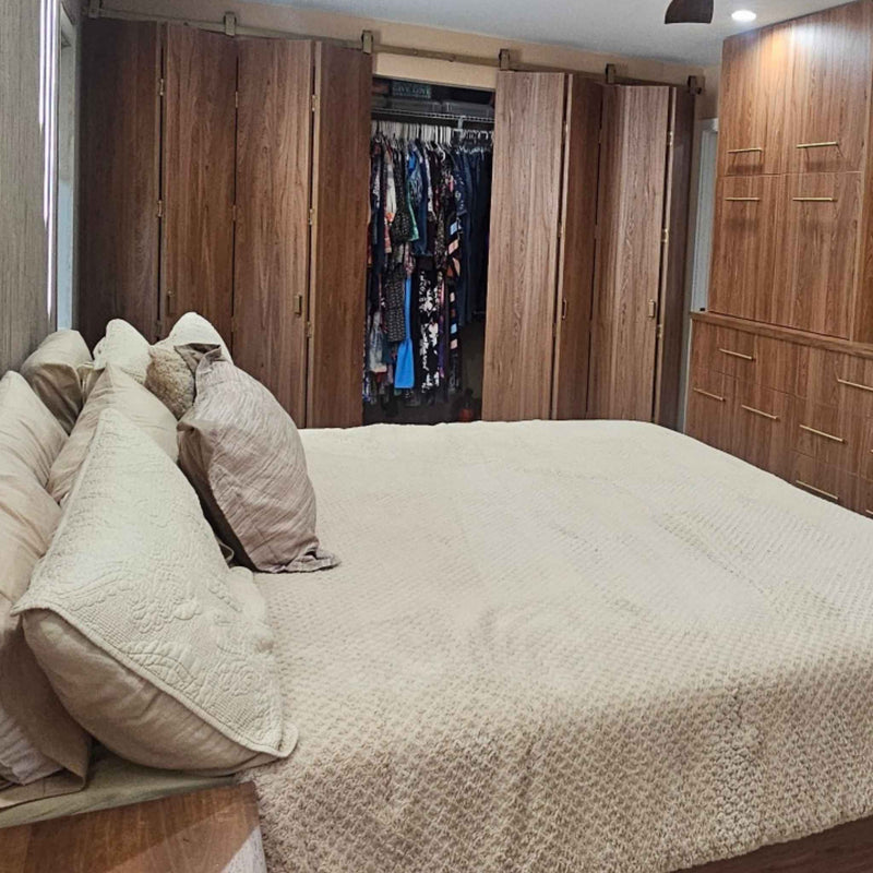 A customer install of an 8-door bi-parting bifold barn door system in a bedroom, featuring J Top Mount hardware in a Jacobs Gold finish.