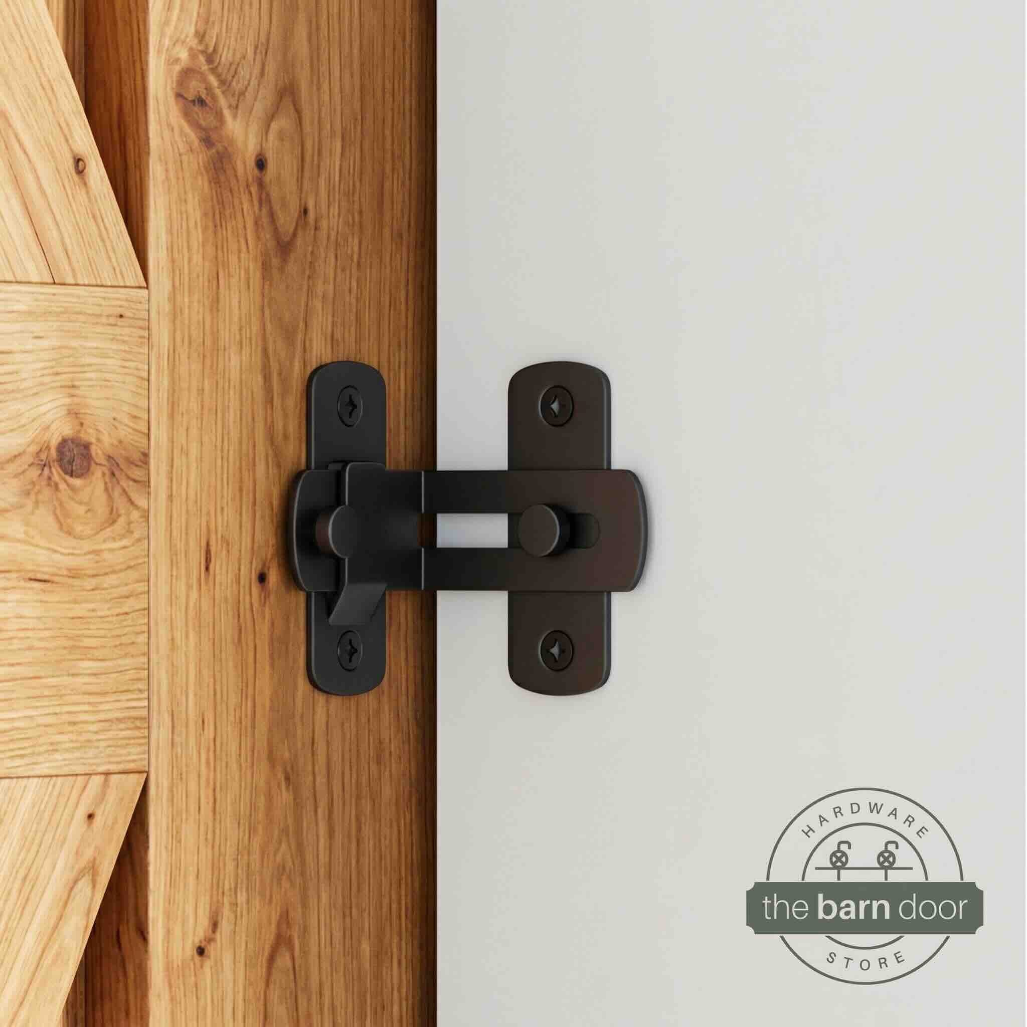 Matte black 90-degree barn door latch installed on a sliding barn door and white wall
