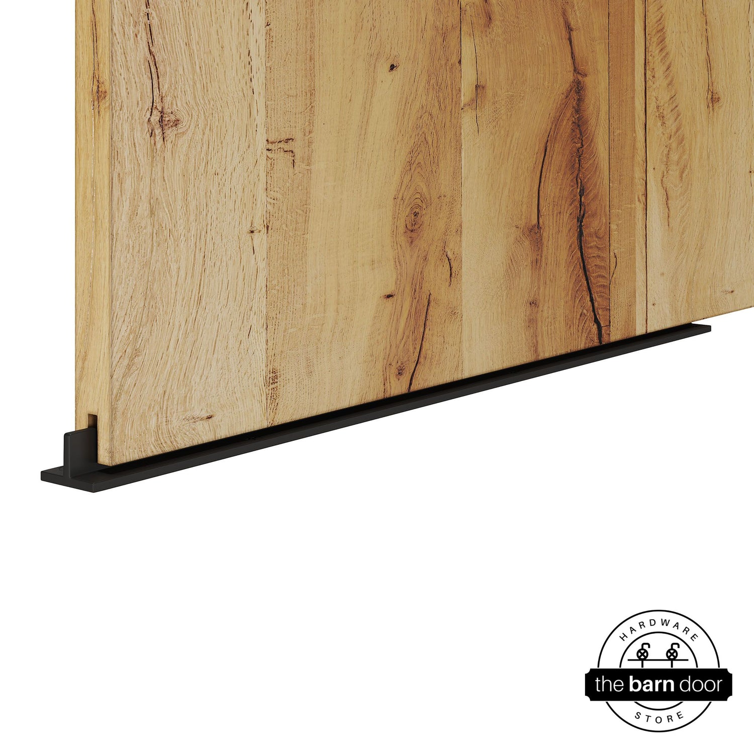Black continuous T-guide floor track for barn doors by The Barn Door Hardware Store. Close-up of a heavy-duty bottom floor guide installed on a rustic wood door for stabilization and smooth sliding operation.