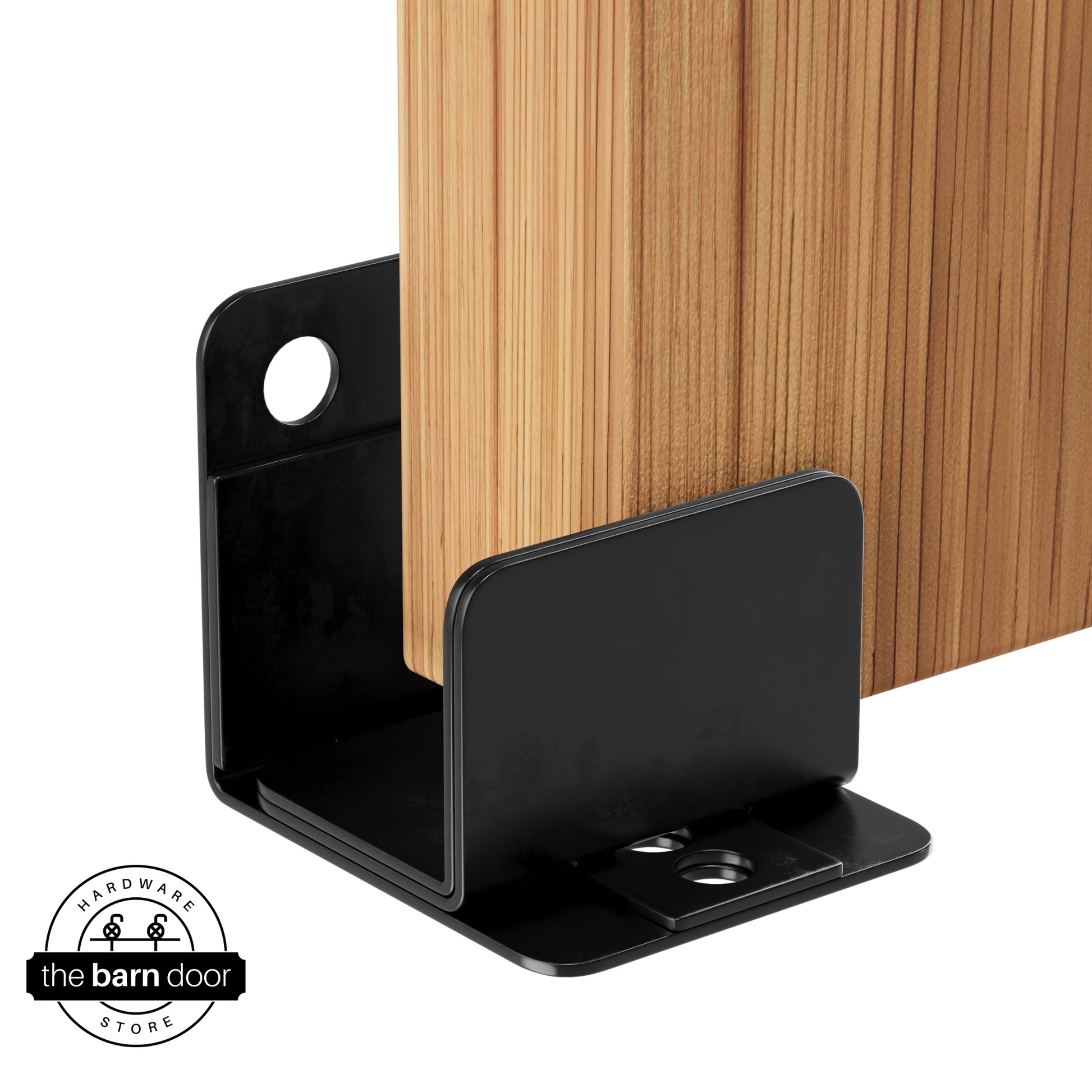 A black U-shaped floor guide with a side plate, holding a light wood barn door in place.