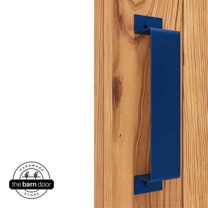 A blue, arch-shaped barn door handle is mounted on a light-colored wooden door with a vertical grain pattern.