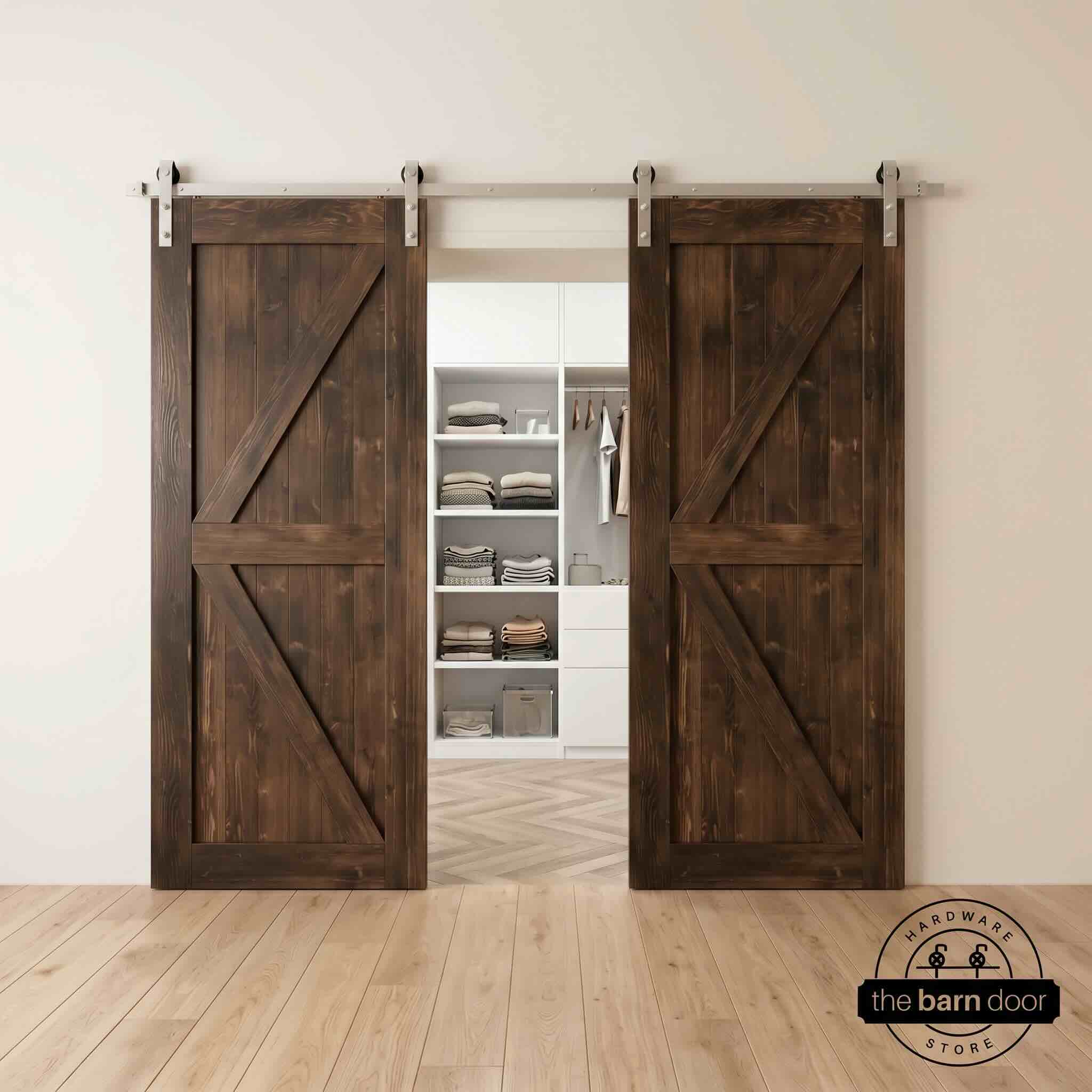 Two wood double barn doors with a two-panel vertical plank design in a dark walnut stain, installed with brushed nickel sliding hardware, partially revealing a living room area.
