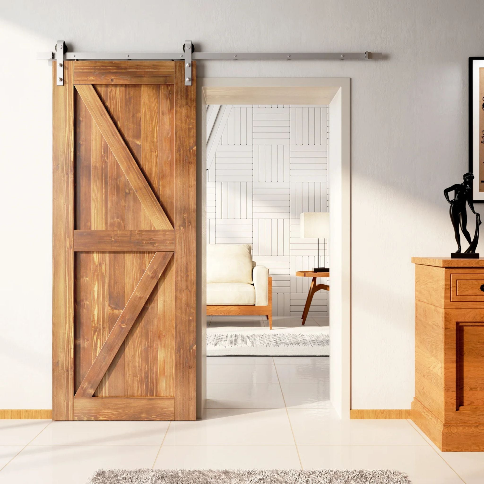 Rustic barn door with a Z-brace design in a light, reddish-brown Early American stain, installed with brushed nickel sliding hardware, partially revealing a living room with white tiled walls.