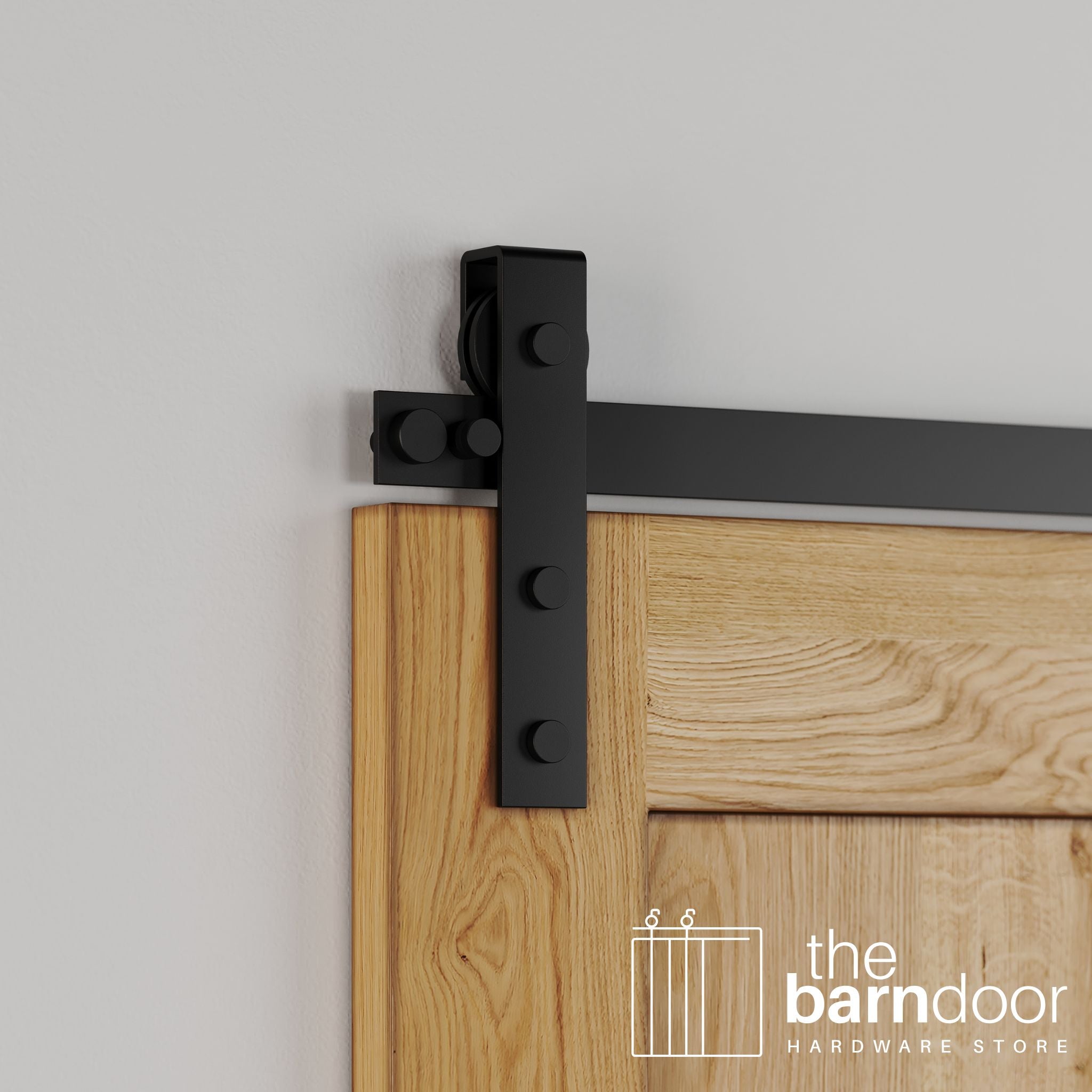 Close-up of Black Stainless Steel Flat Top Strap barn door hardware installed on a natural wood door, showing the strap design and roller.