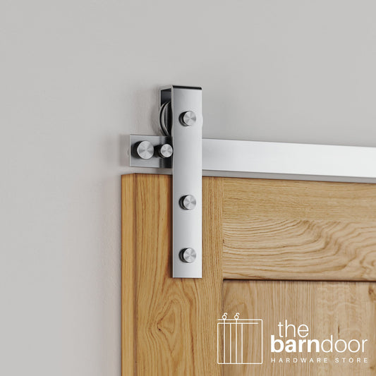 Close-up of Stainless Steel Flat Top Strap barn door hardware installed on a natural wood door, emphasizing the clean, contemporary metal finish.