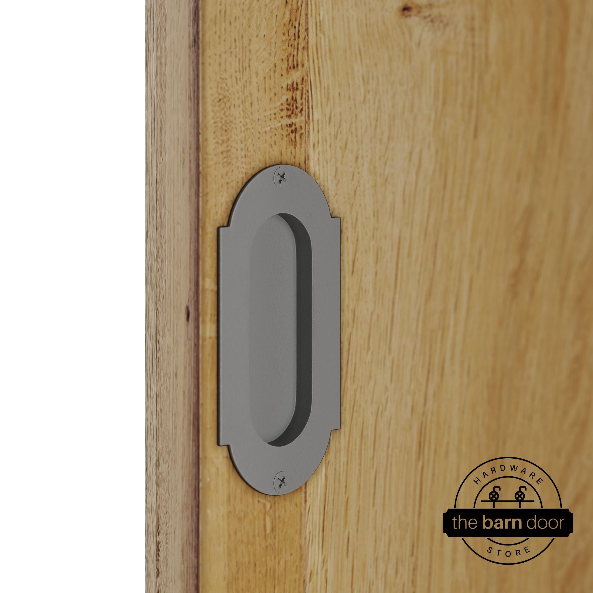 Flint gray flush pull handle with full radius wings mounted on a light oak barn door, brushed silver finish with oval recessed grip and four mounting screws
